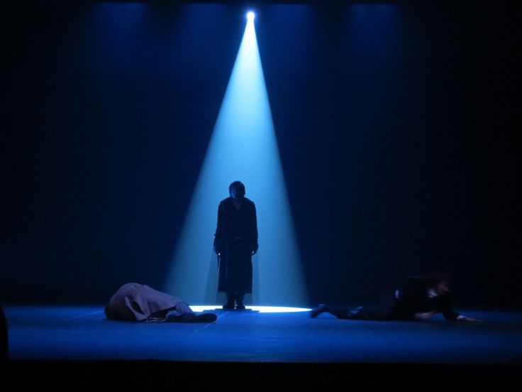 a man standing in the middle of a stage with two people laying on the ground