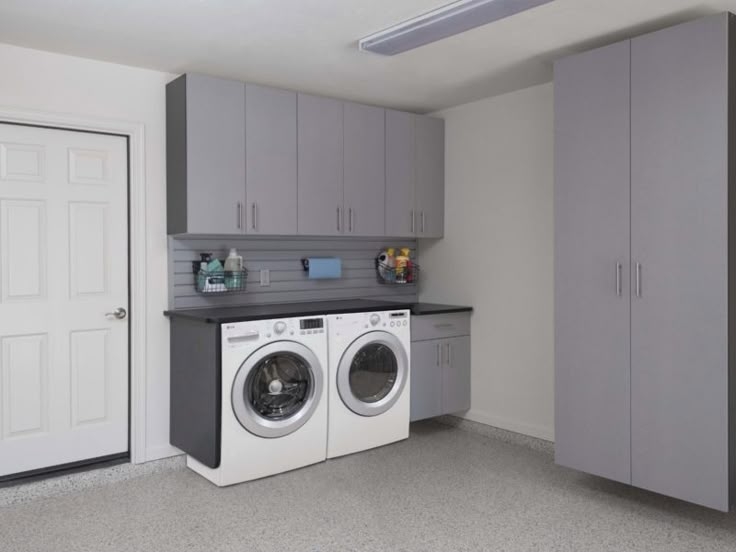 a washer and dryer are in the middle of a room with gray cabinets