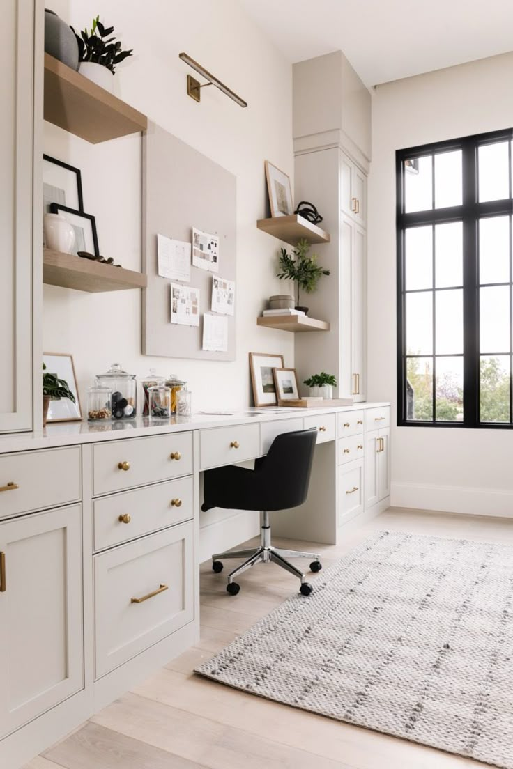 a white desk and chair in a room next to a window with black framed windows