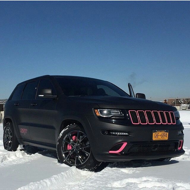 a black jeep parked in the snow with bright pink accents on it's grille