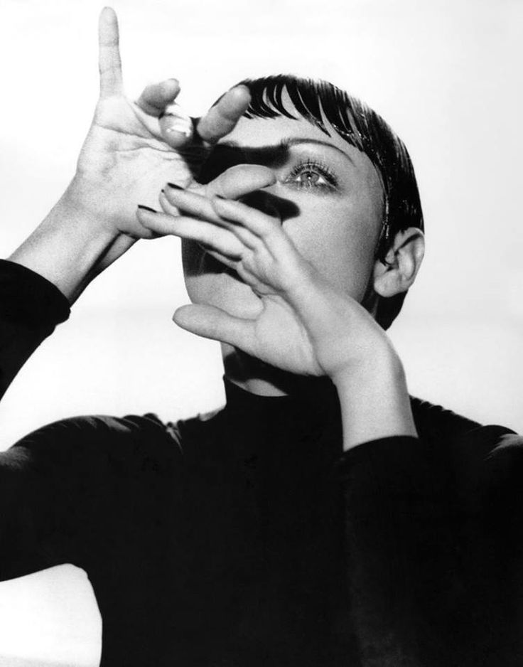 black and white photograph of a woman holding her hands up to her face while making the peace sign