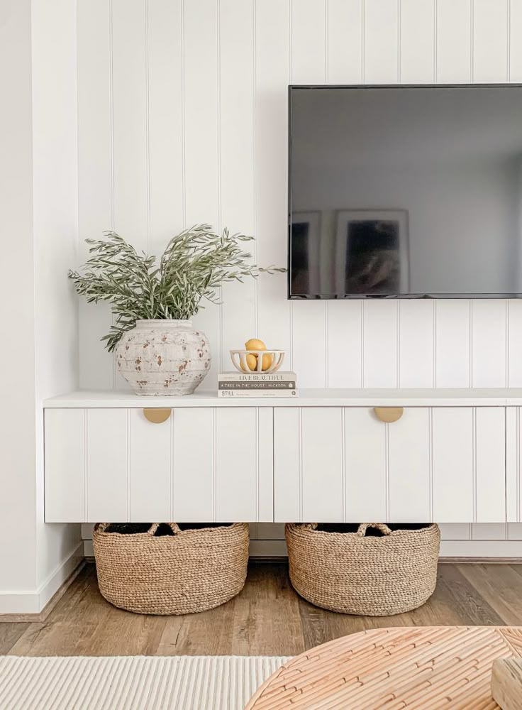 a flat screen tv mounted to the side of a white wall in a living room