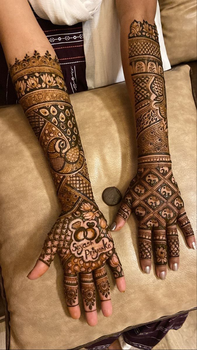 two hands with henna tattoos on them, one is showing off the intricate design