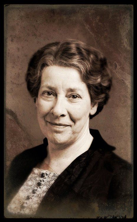 an older woman with curly hair smiling for the camera while wearing a black cardigan