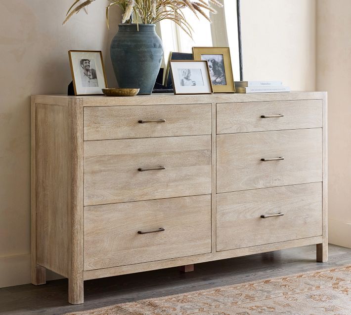 a wooden dresser with pictures on top and a potted plant sitting on top of it