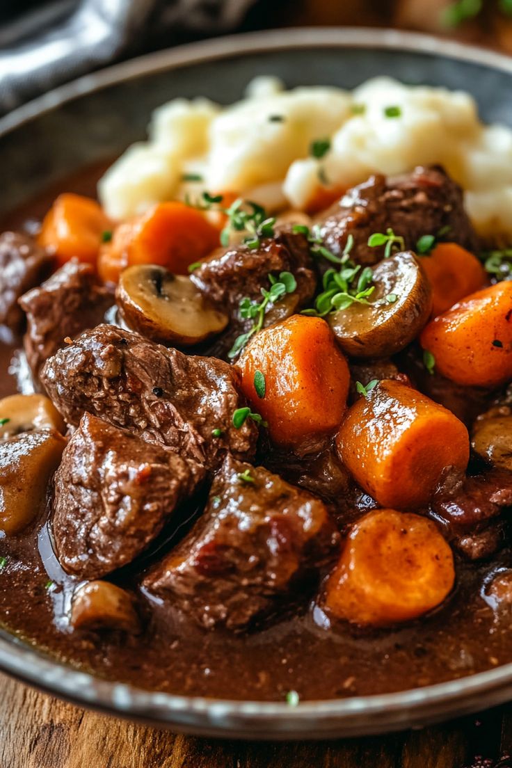 a bowl filled with meat and potatoes on top of a wooden table