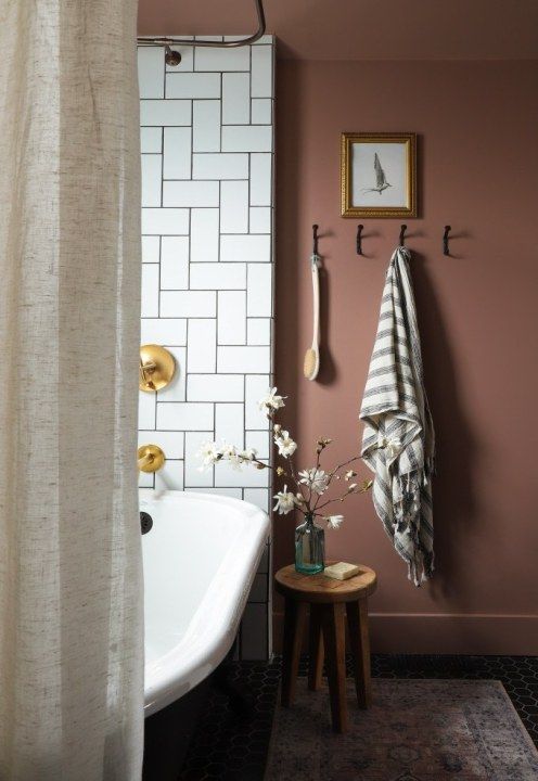 a bathroom with pink walls and white tiles on the wall, along with a bathtub