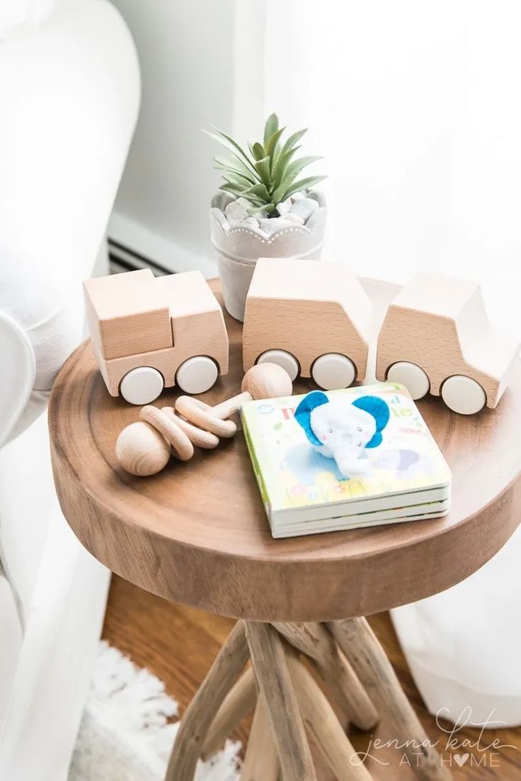 a wooden train set sitting on top of a table next to a potted plant