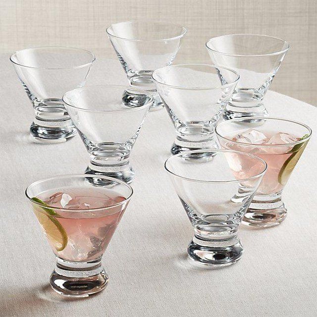 several glasses with different colored liquids in them on a white tablecloth and one is empty