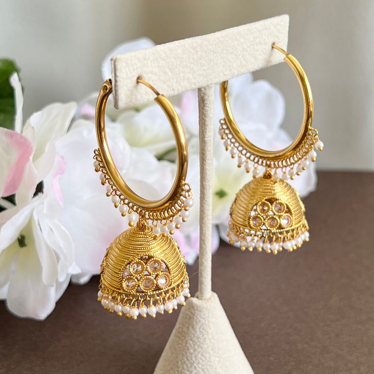 "A stunning pair of designer gold polki jhumka hoop earrings. These mesmerizing gold-plated jhumka hoops are the perfect way to add a touch of fashionable glamour to your look. The unique design includes carved polki detailing and intricate beading that highlights the hoops' curved etching. These beauties will leave a lasting impression. Length 2.5\" | Width 1.5\" Items are carefully packed and ready for gifting. All pictures are taken in natural light please allow for slight variations in color Meenakari Hoop Earrings For Celebrations In Temple Jewelry Style, Meenakari Hoop Earrings For Celebration, Cutdana Hoop Earrings For Diwali Celebration, Kundan Hoop Earrings For Celebration, Kundan Hoop Earrings With Latkans, Festive Round Kundan Hoop Earrings, Gold Kundan Hoop Earrings For Celebration, Temple Jewelry Style Gold Plated Hoop Earrings For Wedding, Festive Gold Hoop Earrings With Cutdana