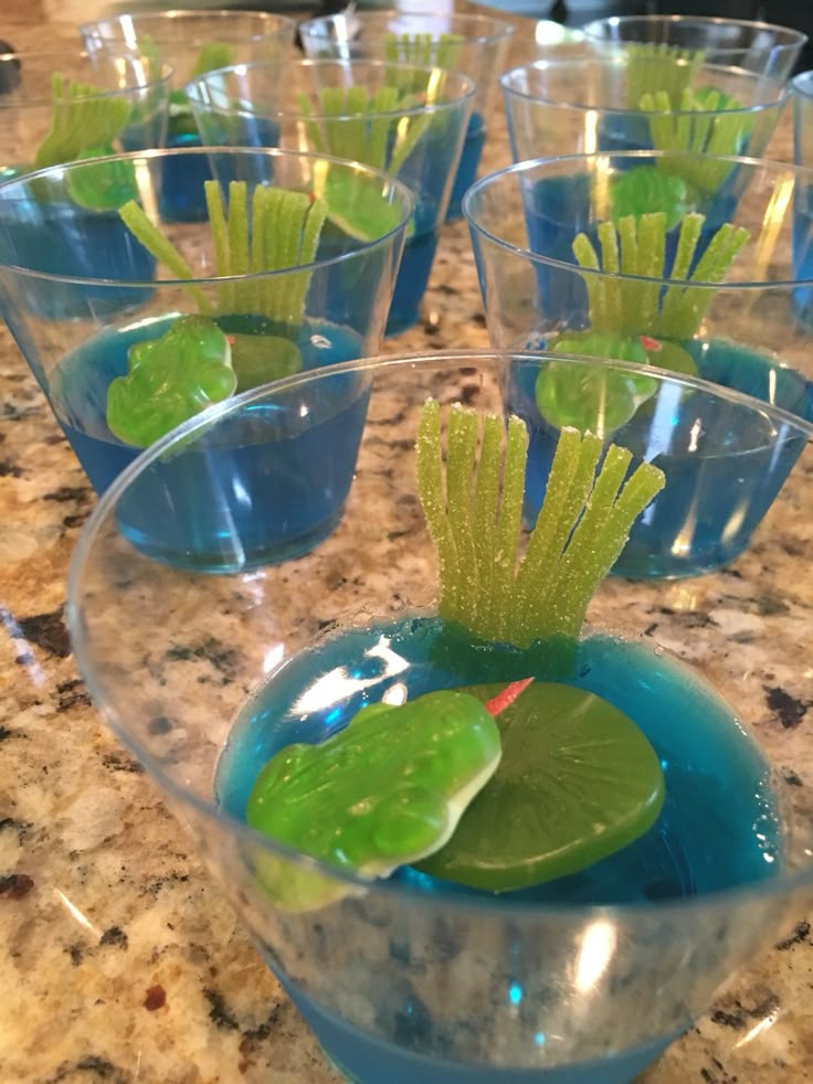 small glass bowls filled with blue water and green leafy plants sitting on top of a counter