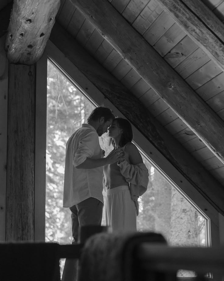 a man and woman standing in front of a window with their arms around each other