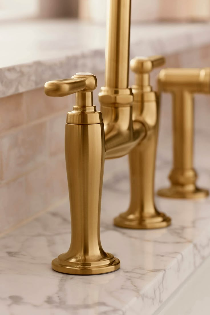 three golden faucets on a marble counter top