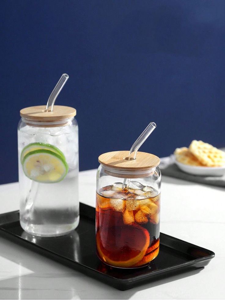 two mason jars filled with drinks on top of a black tray