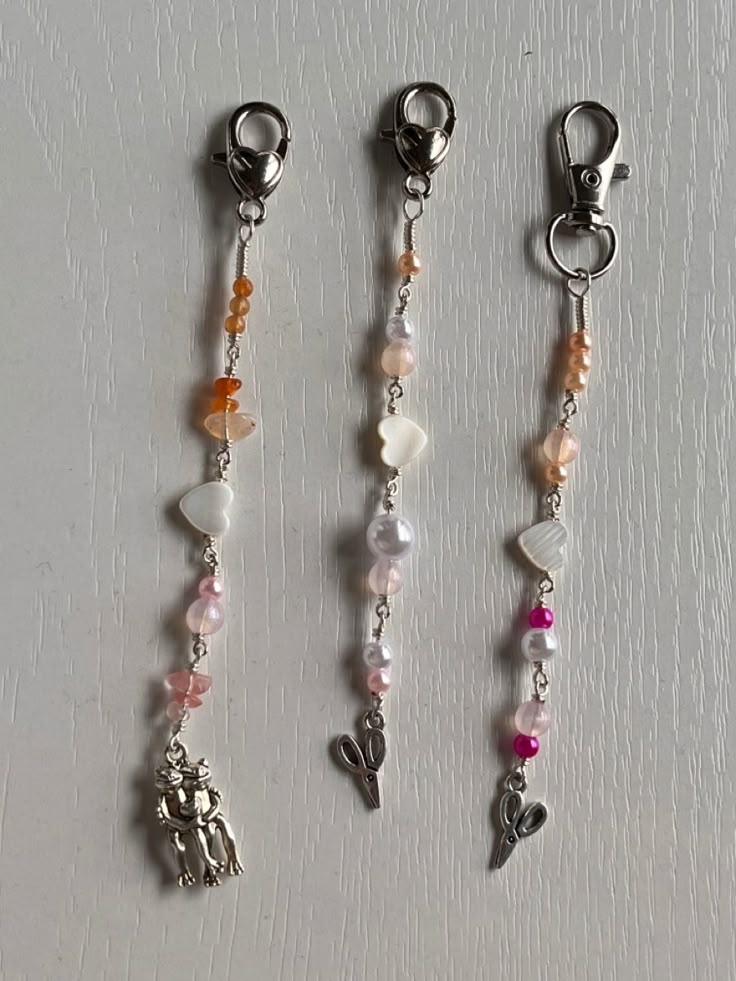 three charms are hanging on a white surface