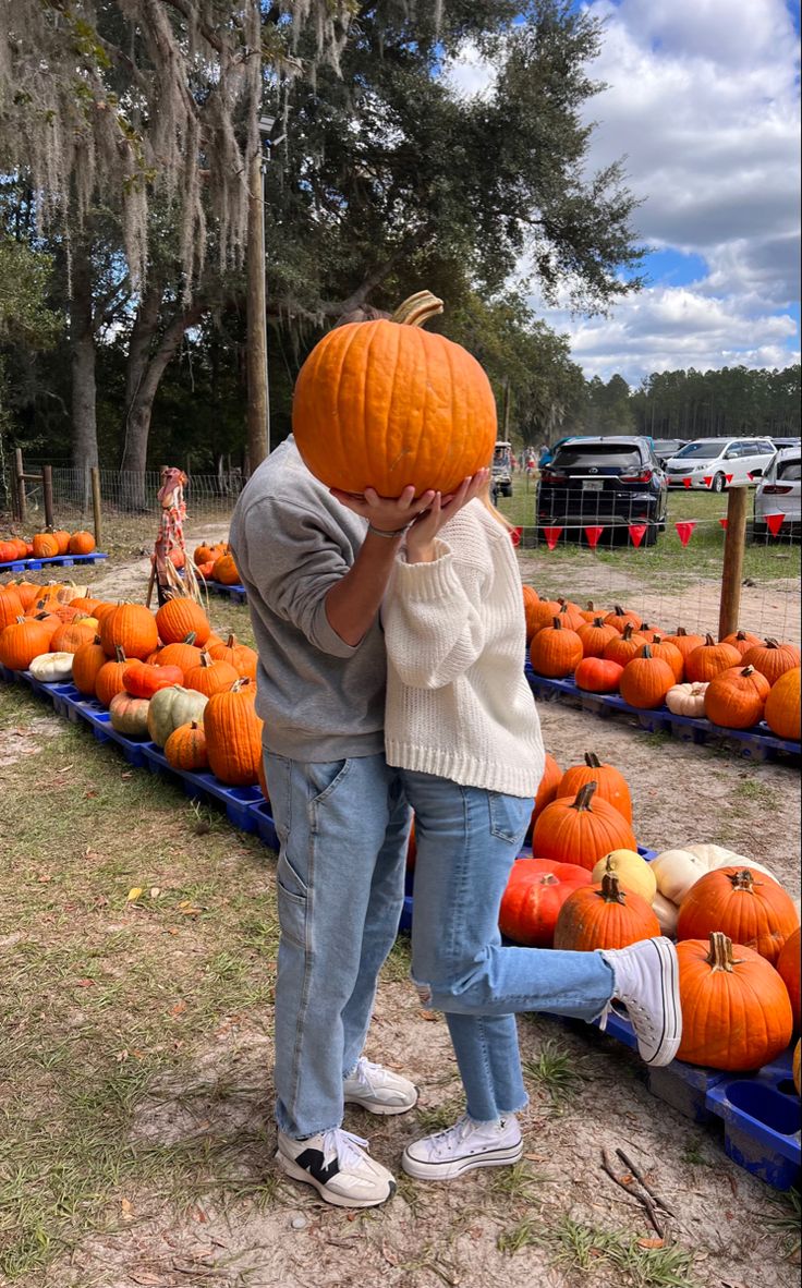 two people standing next to each other with pumpkins in the background