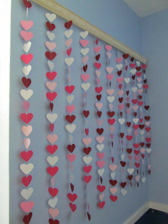 paper hearts hanging from the side of a blue wall in a room with white and pink walls