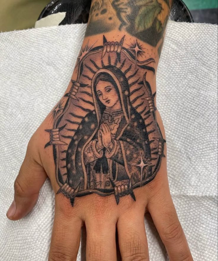 a person's hand with a tattoo on it and a virgin mary in the middle