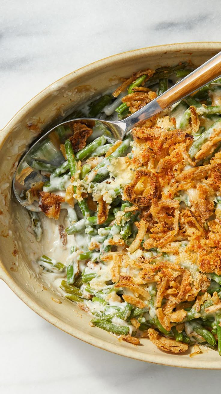 a casserole dish filled with green beans, cheese and bread crumbs