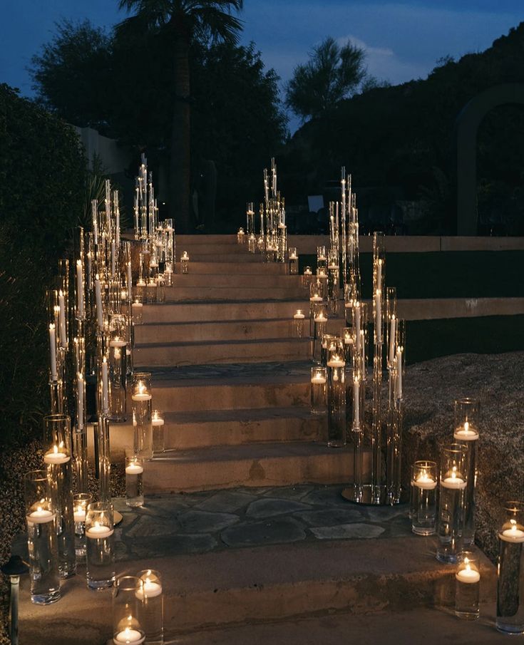 many candles are lit on the steps leading up to an outdoor ceremony venue at night