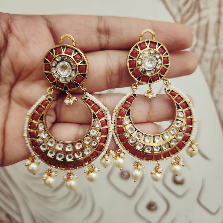 Adorn yourself with these Coral & Kundan Chandbali Earrings, crafted in gold foil. Featuring coral accents paired with Kundan work, these chandbalis blend traditional craftsmanship with timeless elegance. Perfect for special occasions, they add a regal touch to any ensemble. Length: 3" to 3.5" Material: 24Kt gold foil, lac Stones: Kundans, semi precious corals, semi precious pearls Temple Jewelry Style Round Hoop Earrings For Celebration, Temple Jewelry Round Hoop Earrings For Celebration, Red Bridal Earrings With Intricate Design For Diwali, Traditional Chandbalis With Intricate Design For Celebration, Fusion Chandbali Chandelier Earrings For Gifts, Fusion Chandbali Chandelier Earrings As Gift, Fusion Style Chandbali Chandelier Earrings As Gift, Fusion Kundan Chandbali Earrings, Fusion Style Kundan Chandbali Earrings