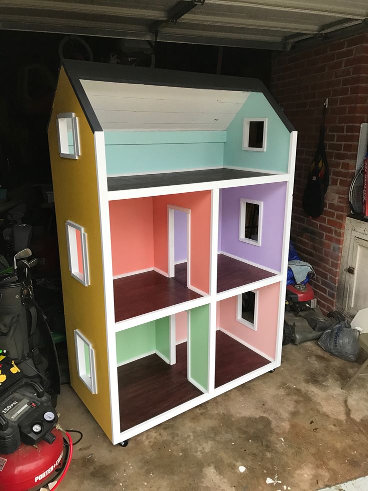 a multicolored doll house built into the side of a garage