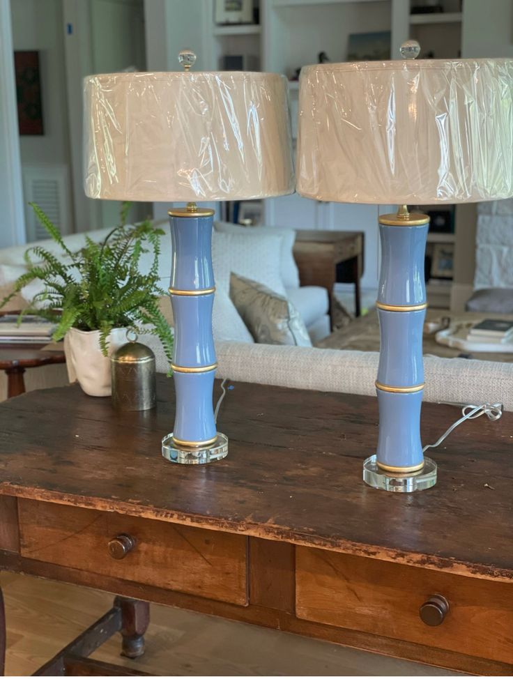 two blue lamps sitting on top of a wooden table