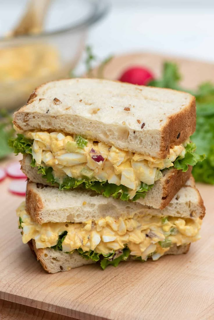 two sandwiches stacked on top of each other with lettuce and eggs in the middle