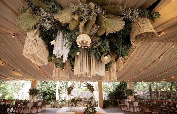 the inside of a tent decorated with flowers and greenery