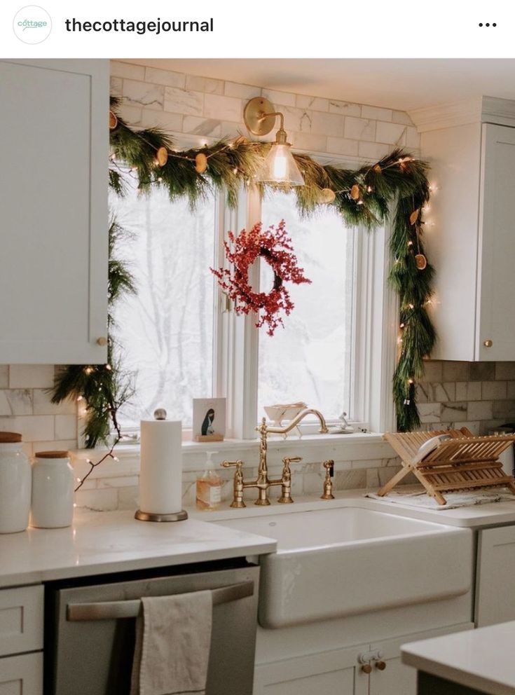 a kitchen decorated for christmas with wreaths and lights on the window sill above the sink