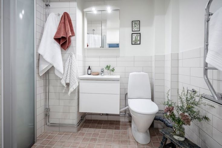 a white toilet sitting next to a sink in a bathroom under a mirror and towel hanging on the wall