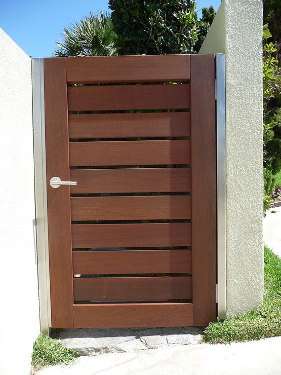 an open wooden door on the side of a building with grass in front of it