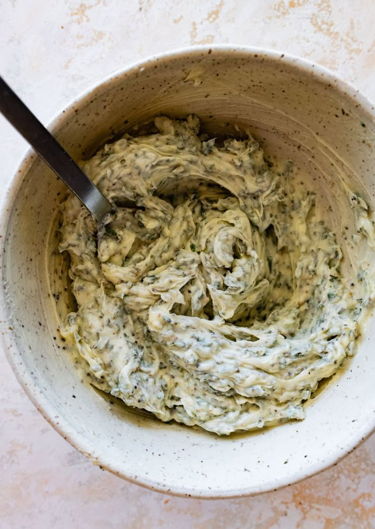 a white bowl filled with green food on top of a table