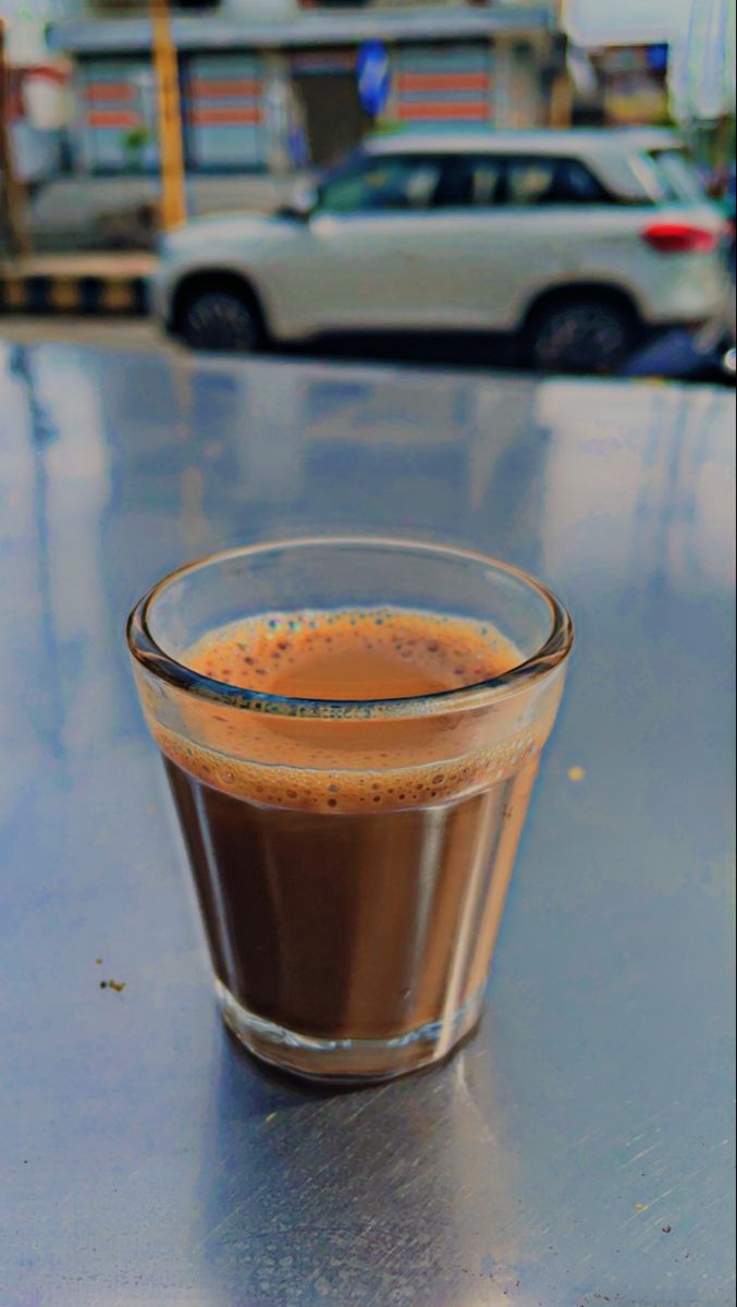 a cup of coffee sitting on top of a table next to a parking lot filled with cars