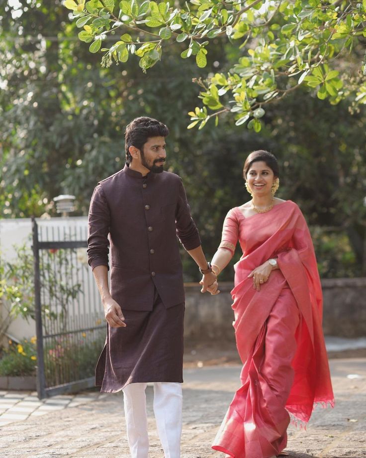 a man and woman holding hands walking down the street