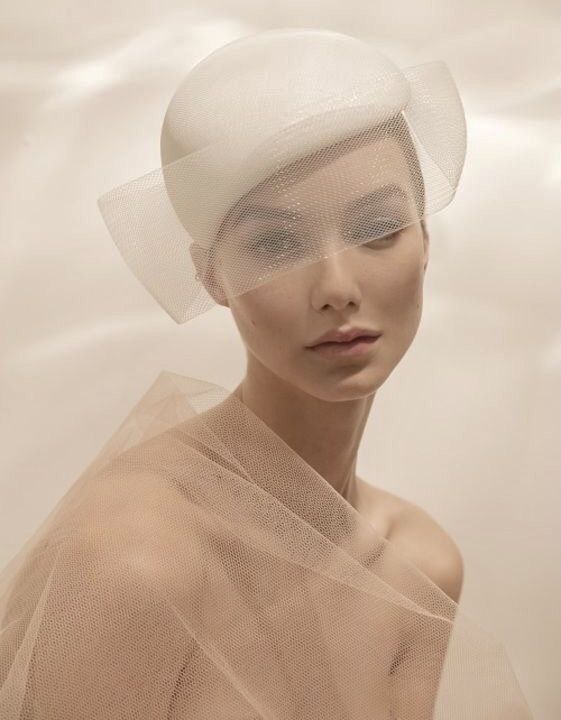 a woman wearing a white hat with veil over her head and eyes covered by sheer fabric