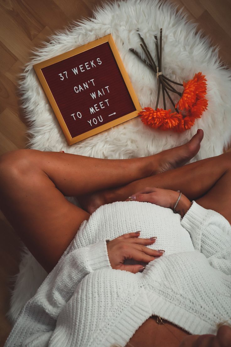 a woman laying on the floor next to a sign that says, st week's can't wait to meet you