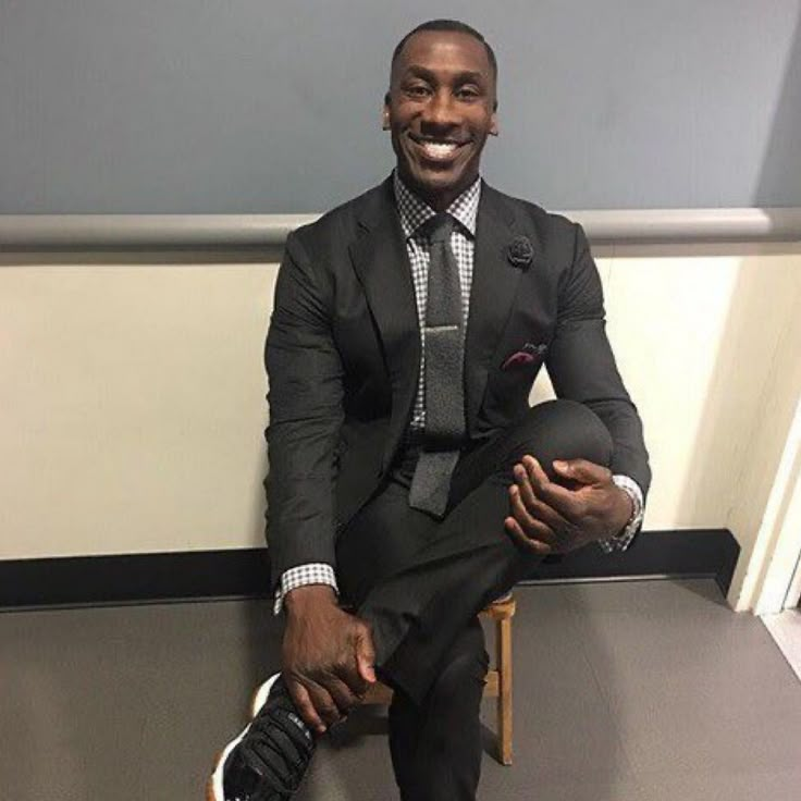 a man in a suit and tie sitting on a chair with his foot up to the ground