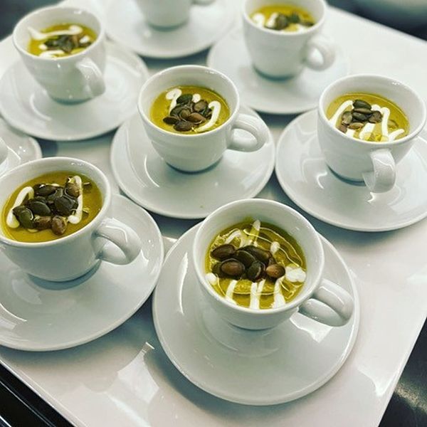 four cups filled with soup on top of white plates