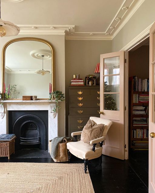 a living room filled with furniture and a fire place in front of a mirror on the wall