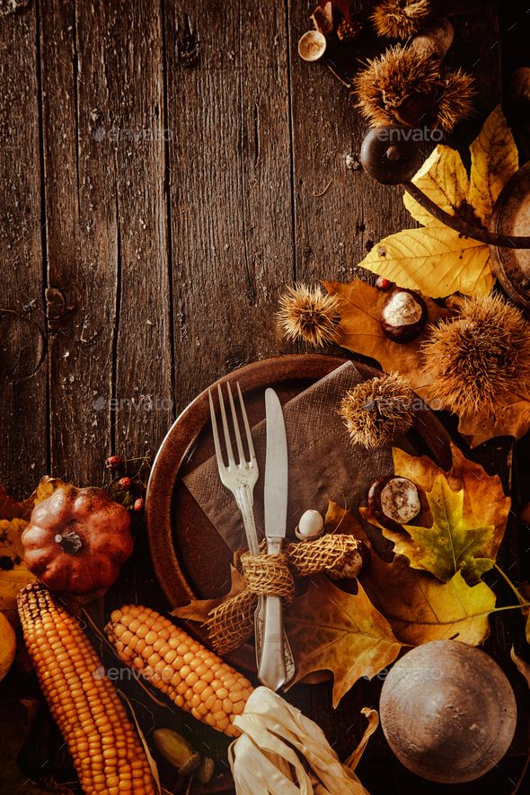 a thanksgiving card with corn, acorns and pumpkins on a wooden table