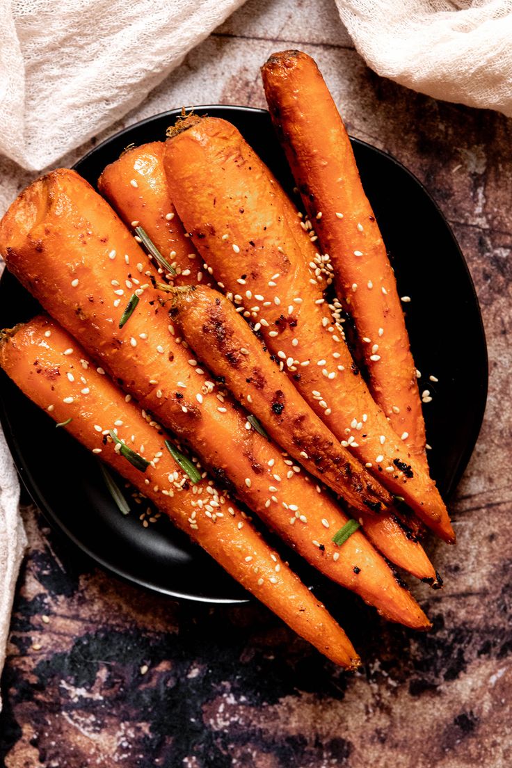 carrots with sesame seeds and seasoning on a black plate