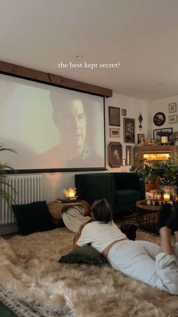 two people laying on the floor in front of a projector screen, watching movies