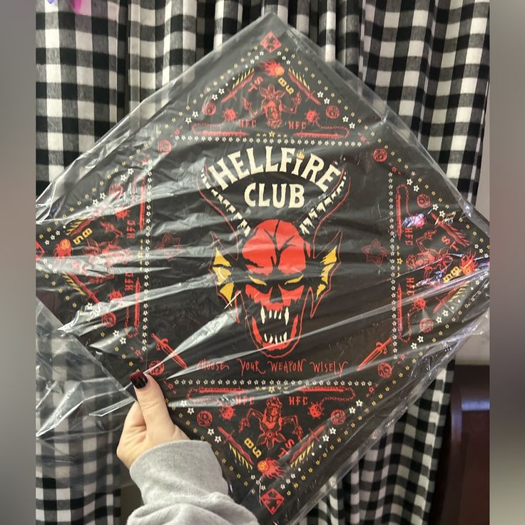 a person holding up a clear umbrella with an image of a skull on it and the words hellfire club