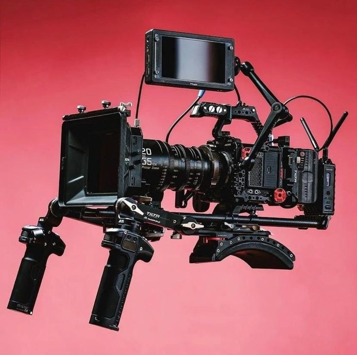 a camera attached to a tripod on a pink background