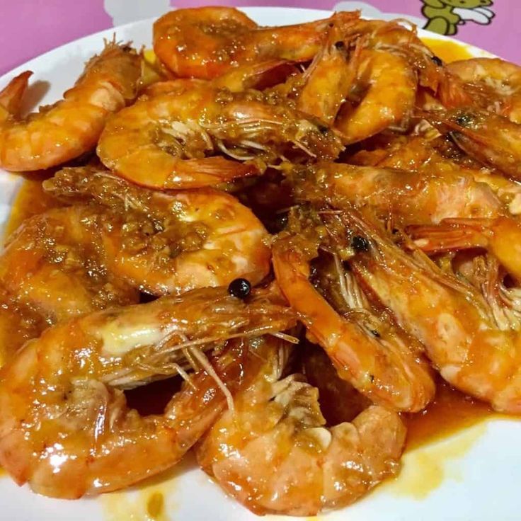 a white plate topped with lots of cooked shrimp