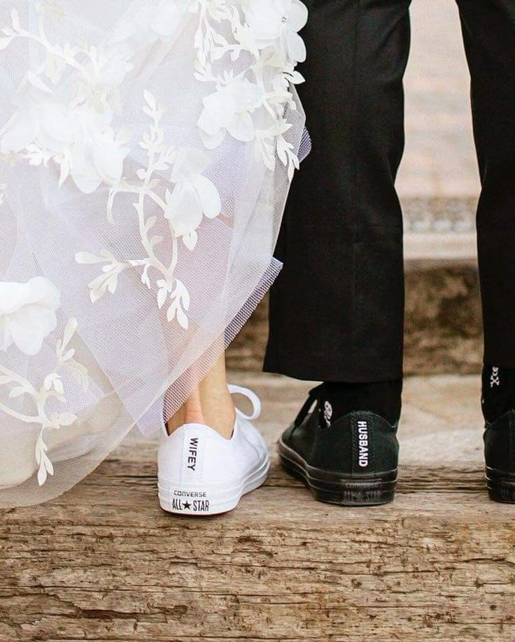 the bride and groom are standing next to each other in their wedding shoes with white flowers on them