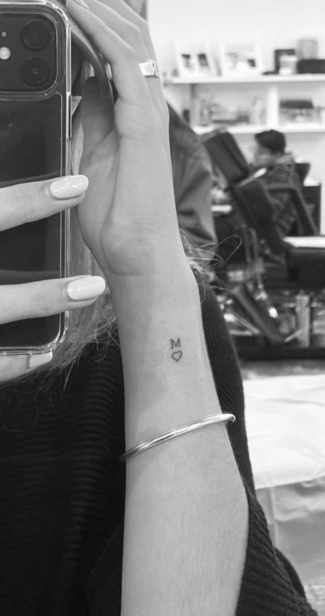 a woman with a tiny butterfly tattoo on her left wrist is taking a selfie