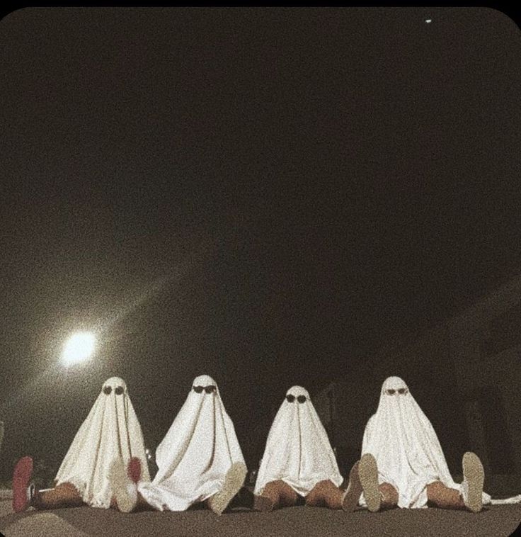 five ghost like figures sitting on the ground