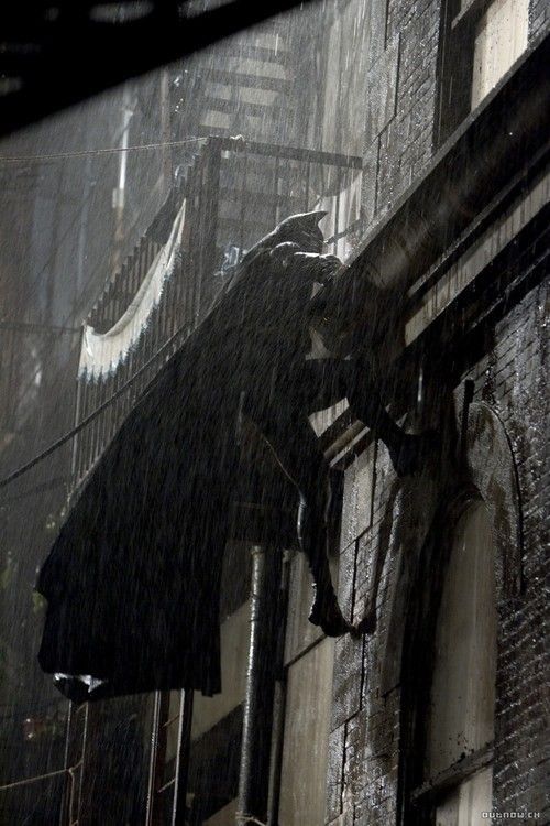 a man is climbing up the side of a building in the rain